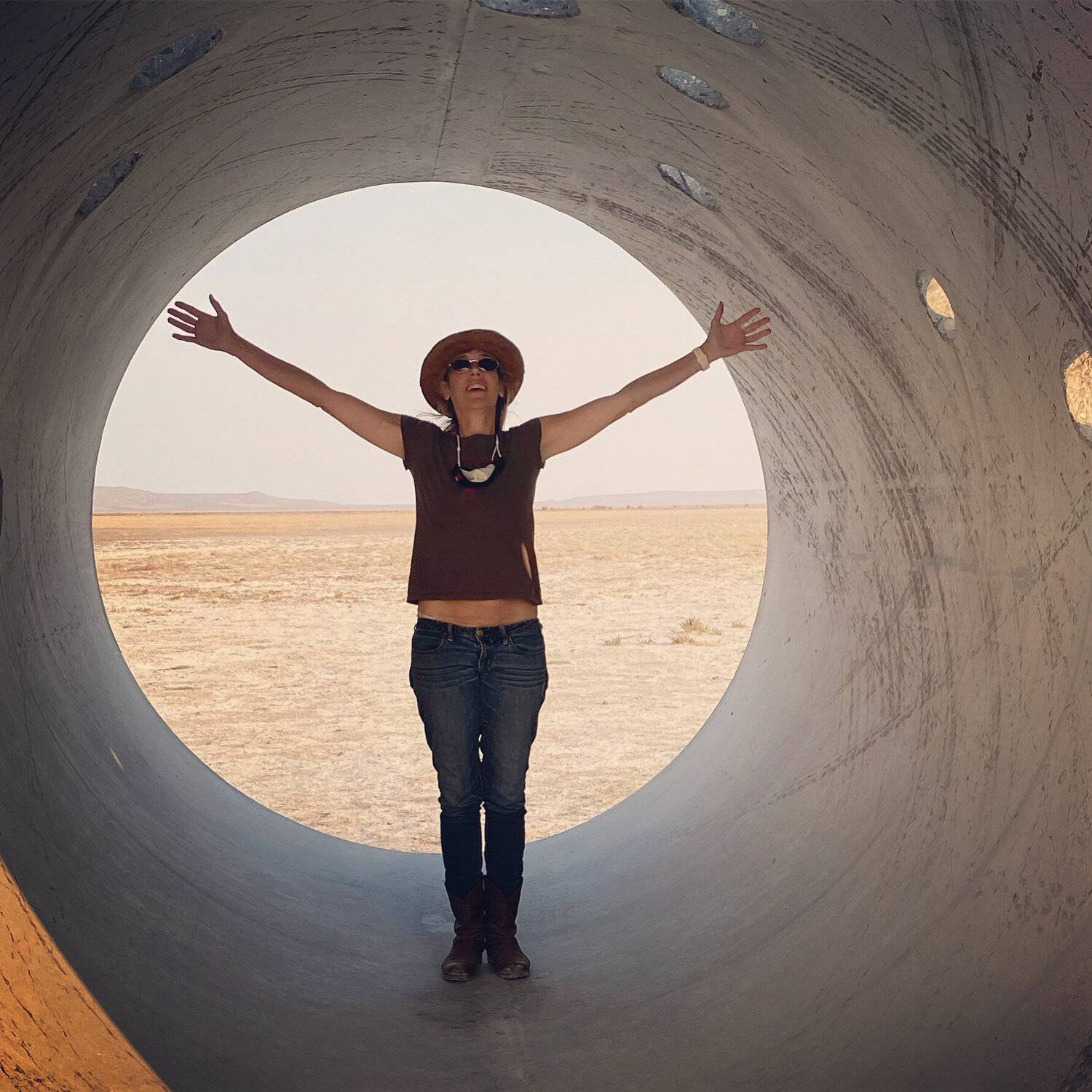 Maria Gambino standing happily with outstretched arms in the Sun Tunnels.